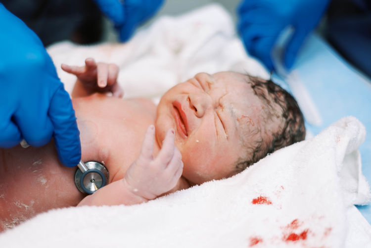 Little baby boy being born via cesarean section.