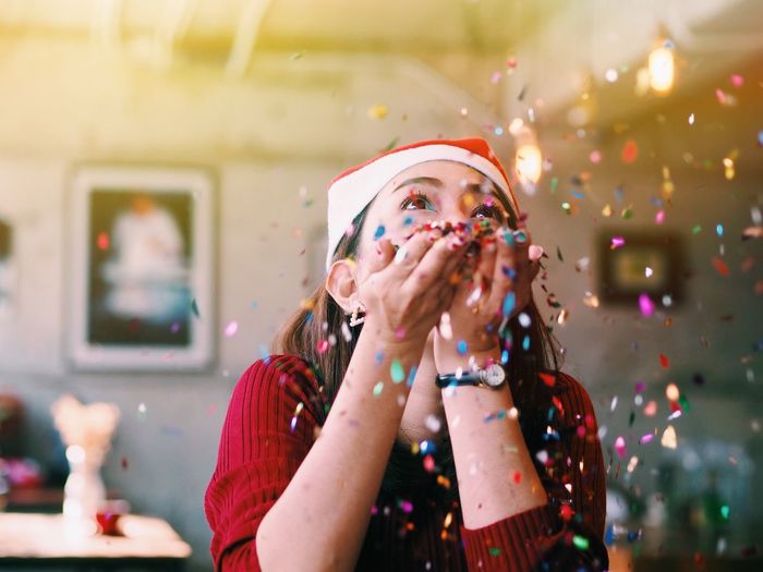 Close-up of young woman blowing confetti