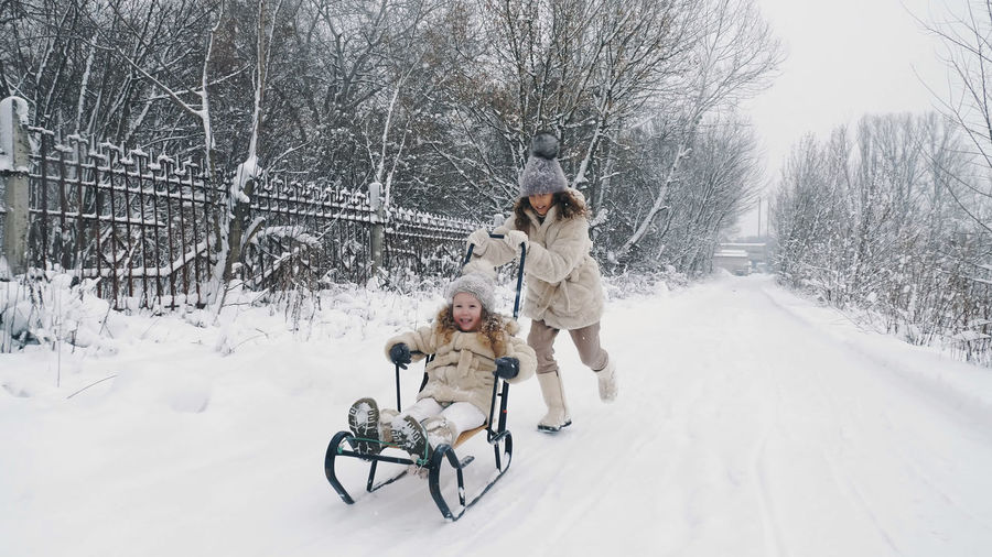 Family sledding in winter. outdoor winter activity. happy, laughing, playful children are enjoying 