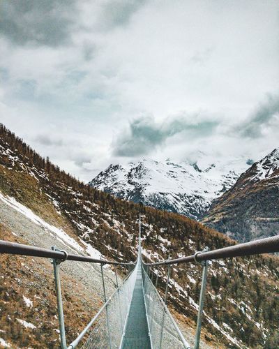 Footbridge against snowcapped mountains during winter