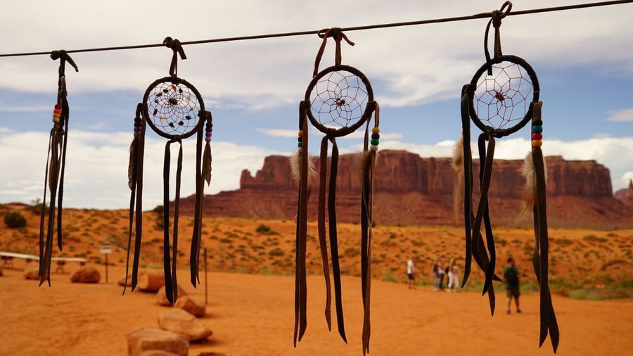 Dreamcatchers hanging on rope at desert against sky