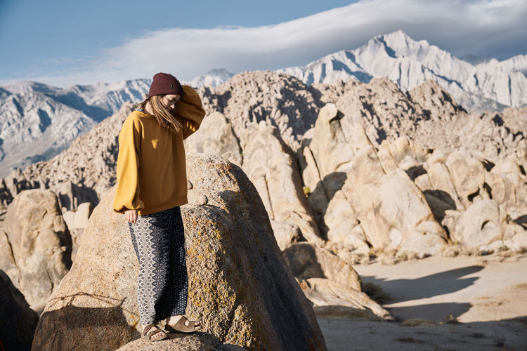 Woman standing on rock in the wind near mountains