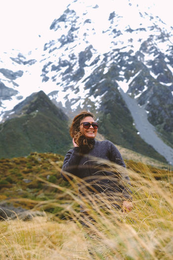 Smiling young woman on land against mountain range