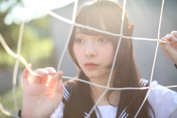 Young woman standing by sports net