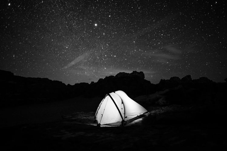 Illuminated tent on field against star field