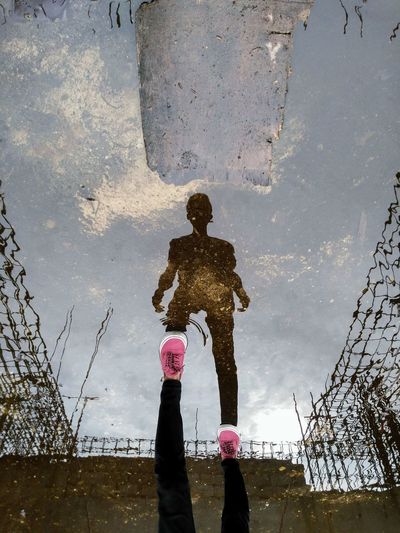 Rear view of man standing against sky reflection