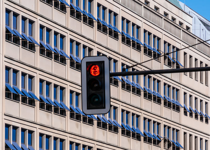 Low angle view of stoplight against building in city