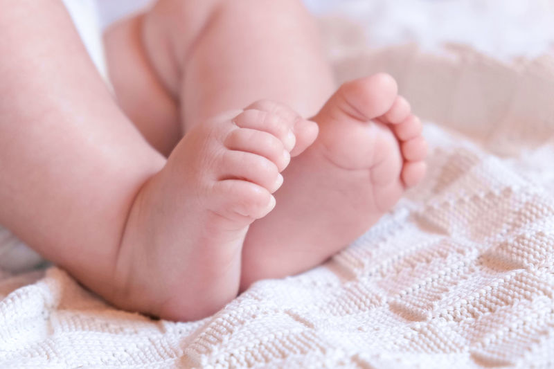 Tiny babies feet on white blanket. close up of small bare feet of baby infant sleeping on soft bed.