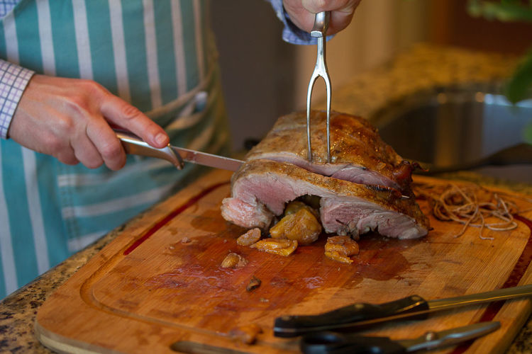 Midsection of man cutting lamb