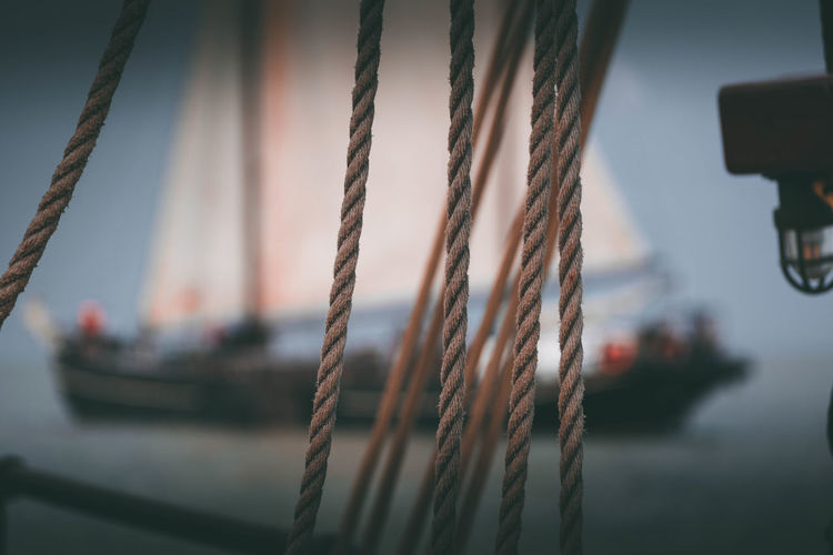 Close-up of rope with blurry sailing ship in background