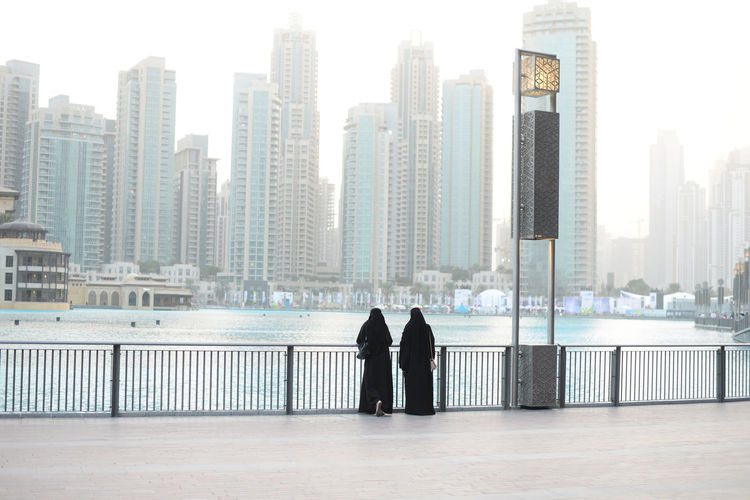 Dubai - skyline at sunrise of dubai business center, two women in united arab emirates
