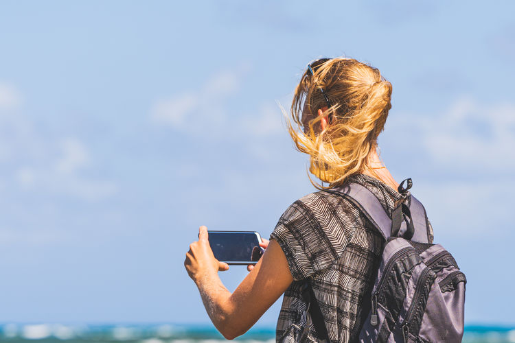 Low angle view of woman looking away against sky