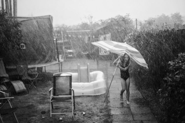 Rear view of woman standing on wet rainy day