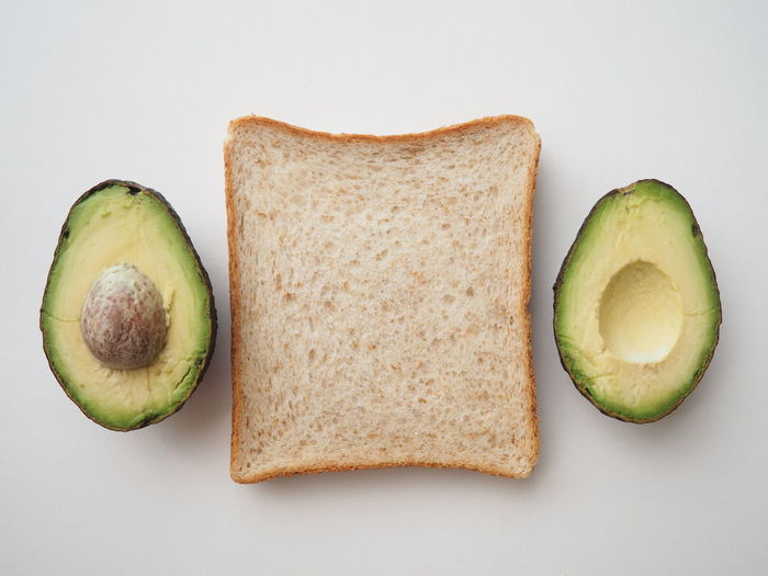 Directly above shot of breakfast with  whole wheat bread and avocado on white background