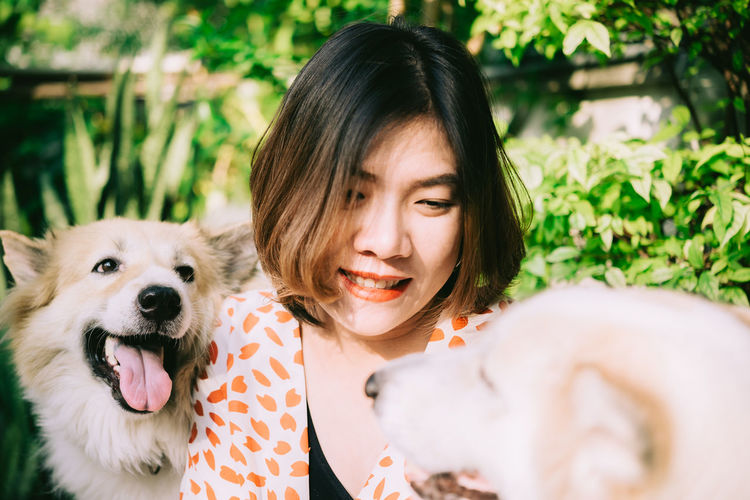 Close-up of smiling woman holding dogs