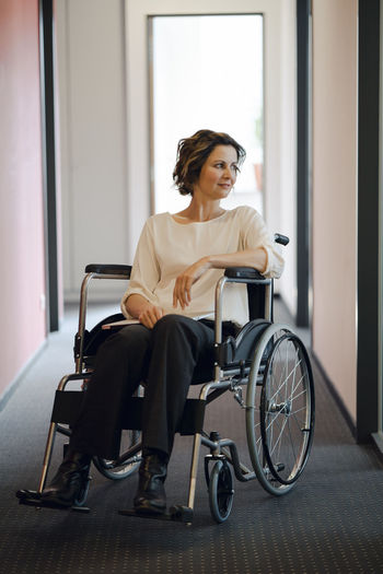 Portrait of young woman sitting on wheelchair