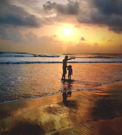 Silhouette of father and daughter on beach