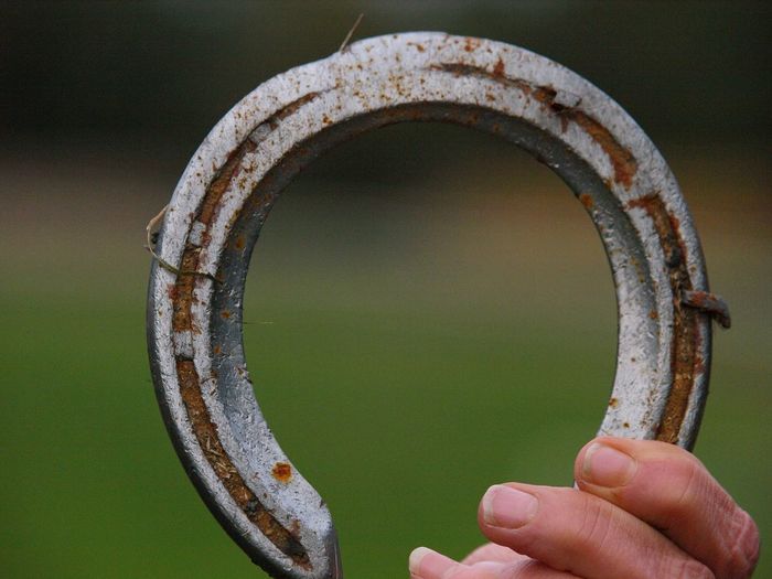 Close-up of hand holding rusty metal horseshoe