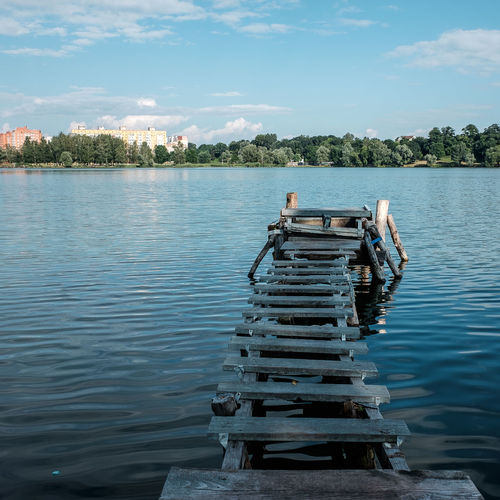 Abandoned wooden pier on lake against sky