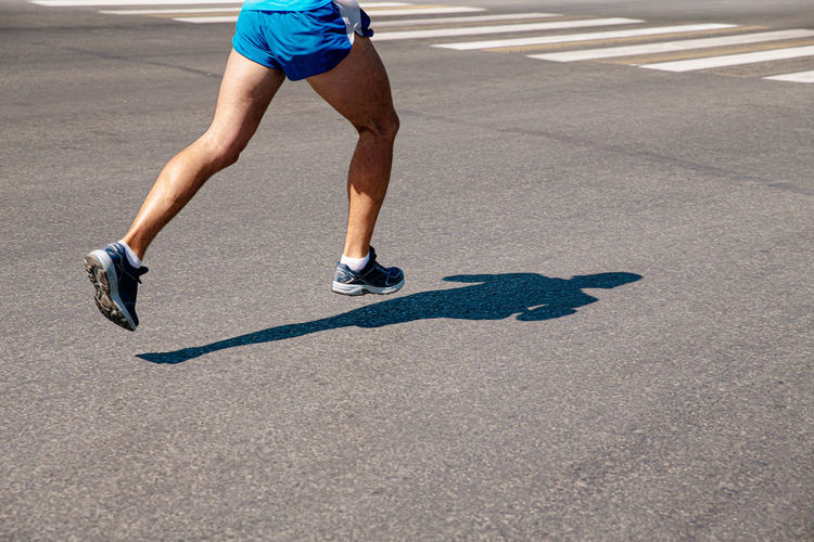 Legs male runner run on gray asphalt marathon