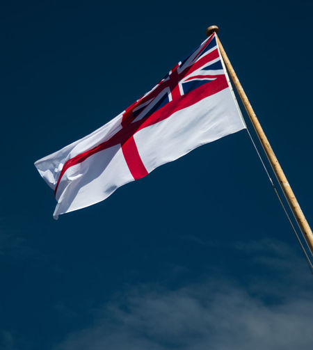 Low angle view of flag waving against blue sky