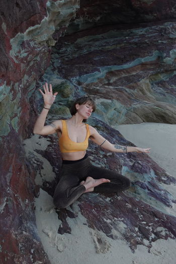 High angle view of woman meditating on rocks at beach