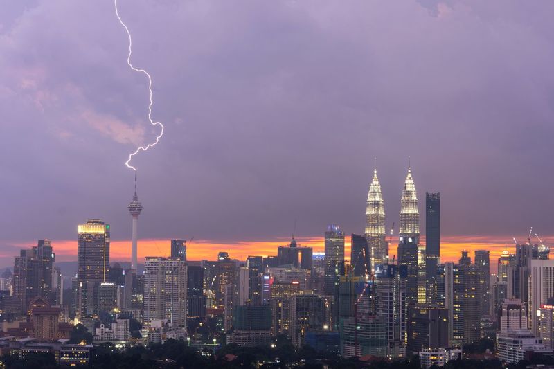View of thunderstorm over cityscape at dusk