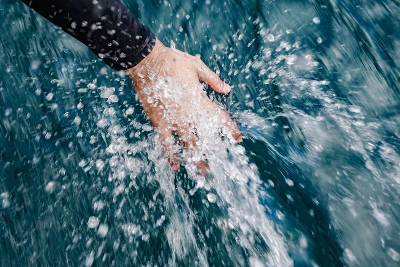 Cropped hand of person splashing water in sea