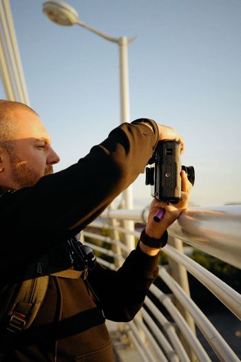 Portrait of man photographing against sky