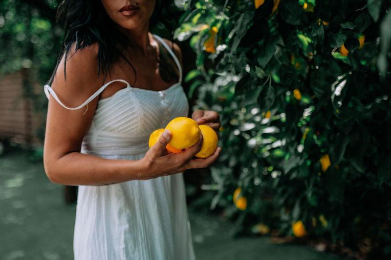 Midsection of woman holding orange while standing outdoors