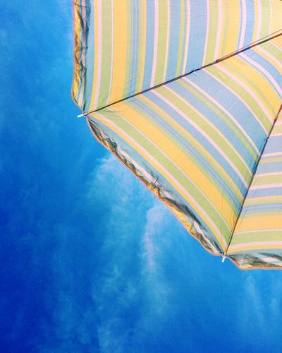 Low angle view of beach umbrella against blue sky