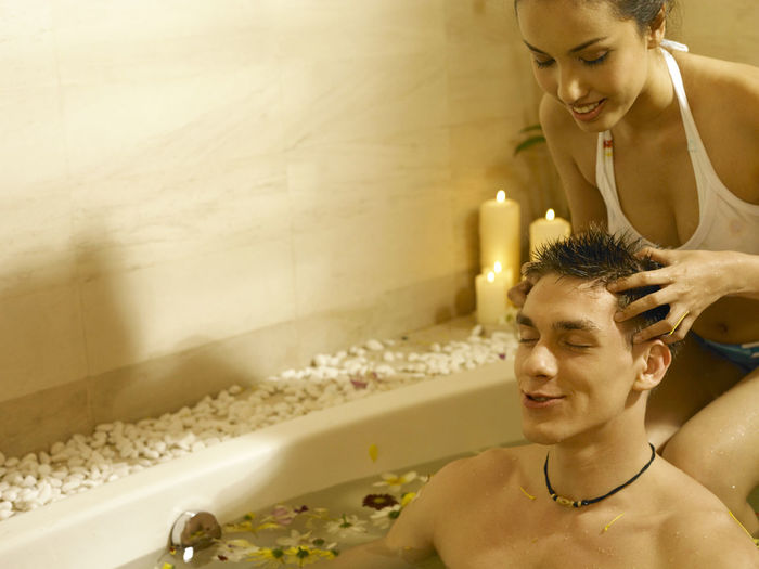 Girlfriend giving head massage to boyfriend in bathtub