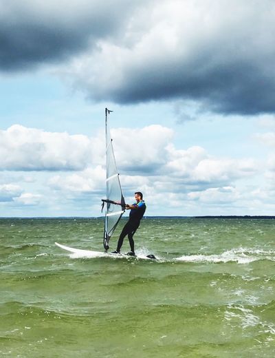 Man windsurfing at sea against sky