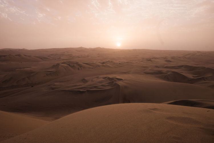 Scenic view of huacachina desert against sky during sunset