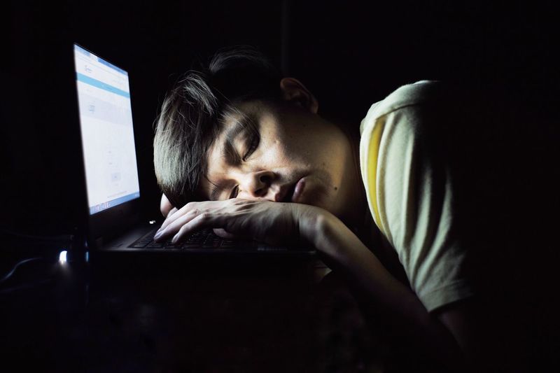 Close-up of tired man sleeping on laptop at home