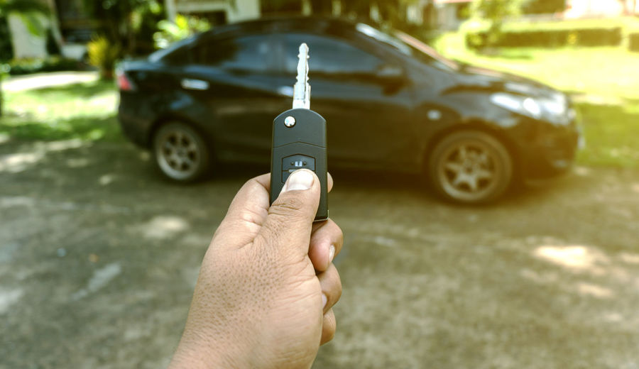 Cropped hand of man holding key against car