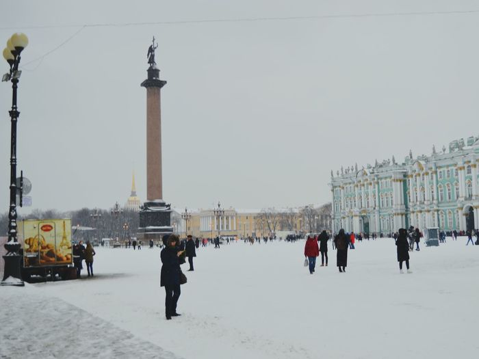People on snow covered city against sky
