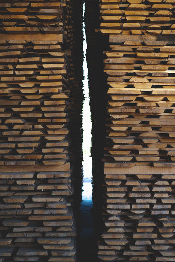 Full frame shot of wooden logs against brick wall