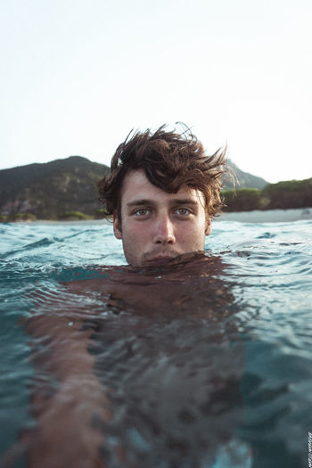 Portrait of young man in sea against clear sky