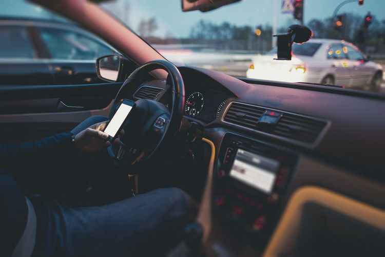 Man using mobile phone in car while waiting in traffic