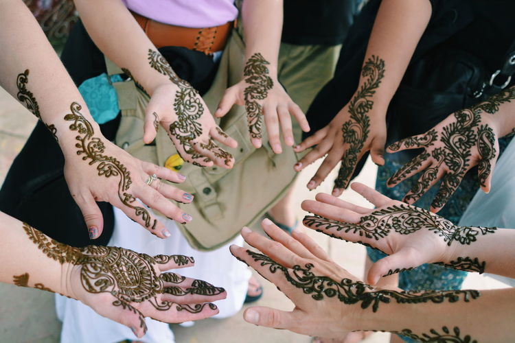 High angle view of people with henna tattoo on hands