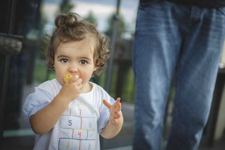 Portrait of cute baby girl eating food while standing outdoors