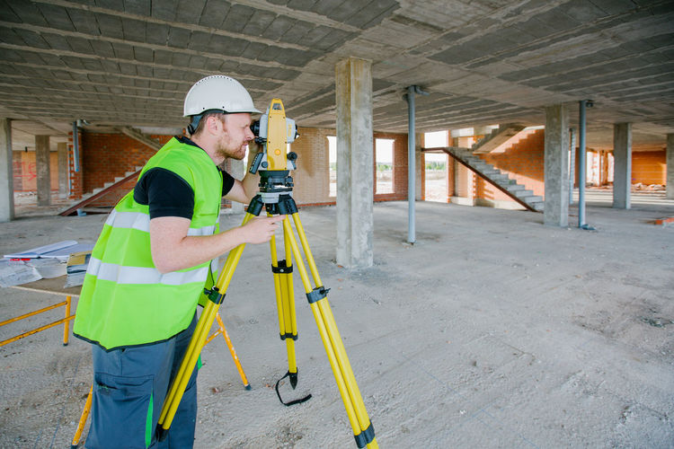 Surveyor engineer working at construction site with measuring equipment (total station)