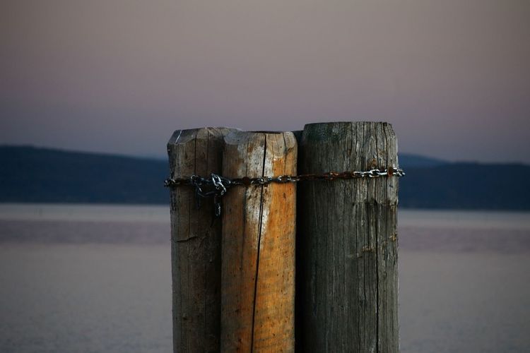 Close-up of wooden post in lake against sky