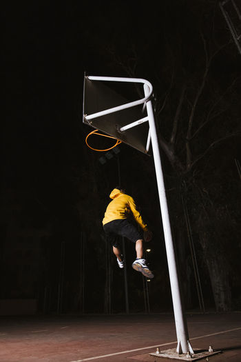 Basketball player in yellow sport clothes jumping and making dunk while training on sports ground