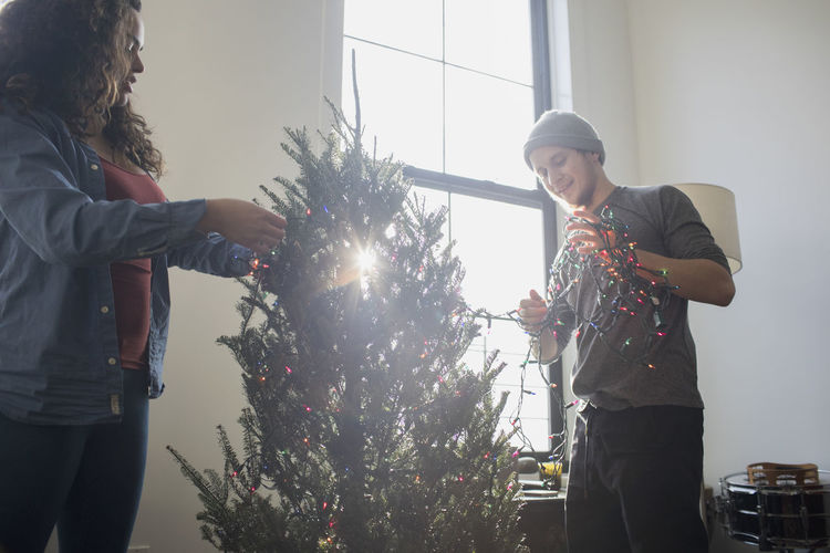 A young woman and man decorating a christmas tree