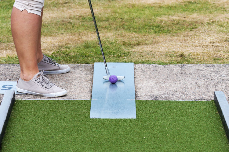 Low section of woman playing at miniature golf