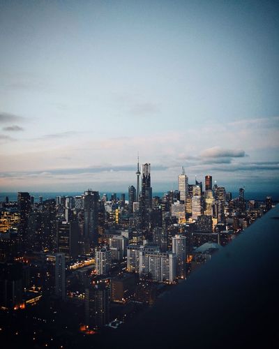 Aerial view of city lit up against sky