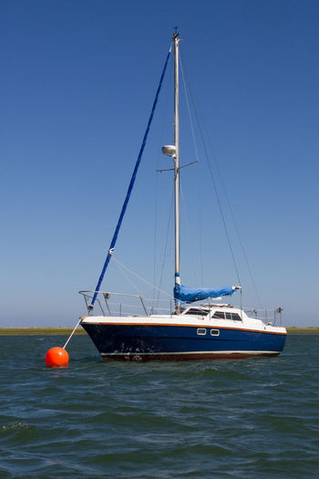 Sailboat sailing on sea against clear blue sky