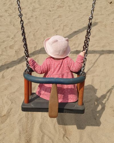 Rear view of girl sitting on swing at playground